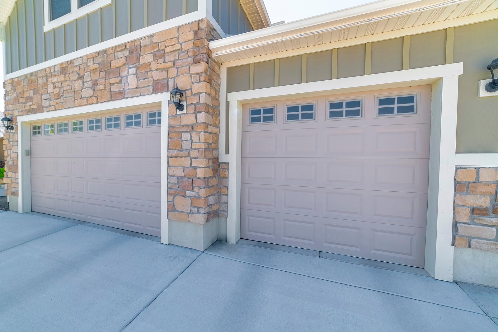 Three car garage exterior with stone veneer and green board and batten siding