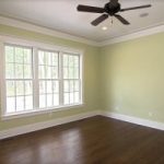 White windows in a living space with hardwood floors and a ceiling fan
