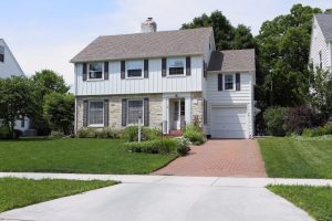 Roof Replacement Waukesha WI Two-story family home with stone and white siding. Large green lawn out front