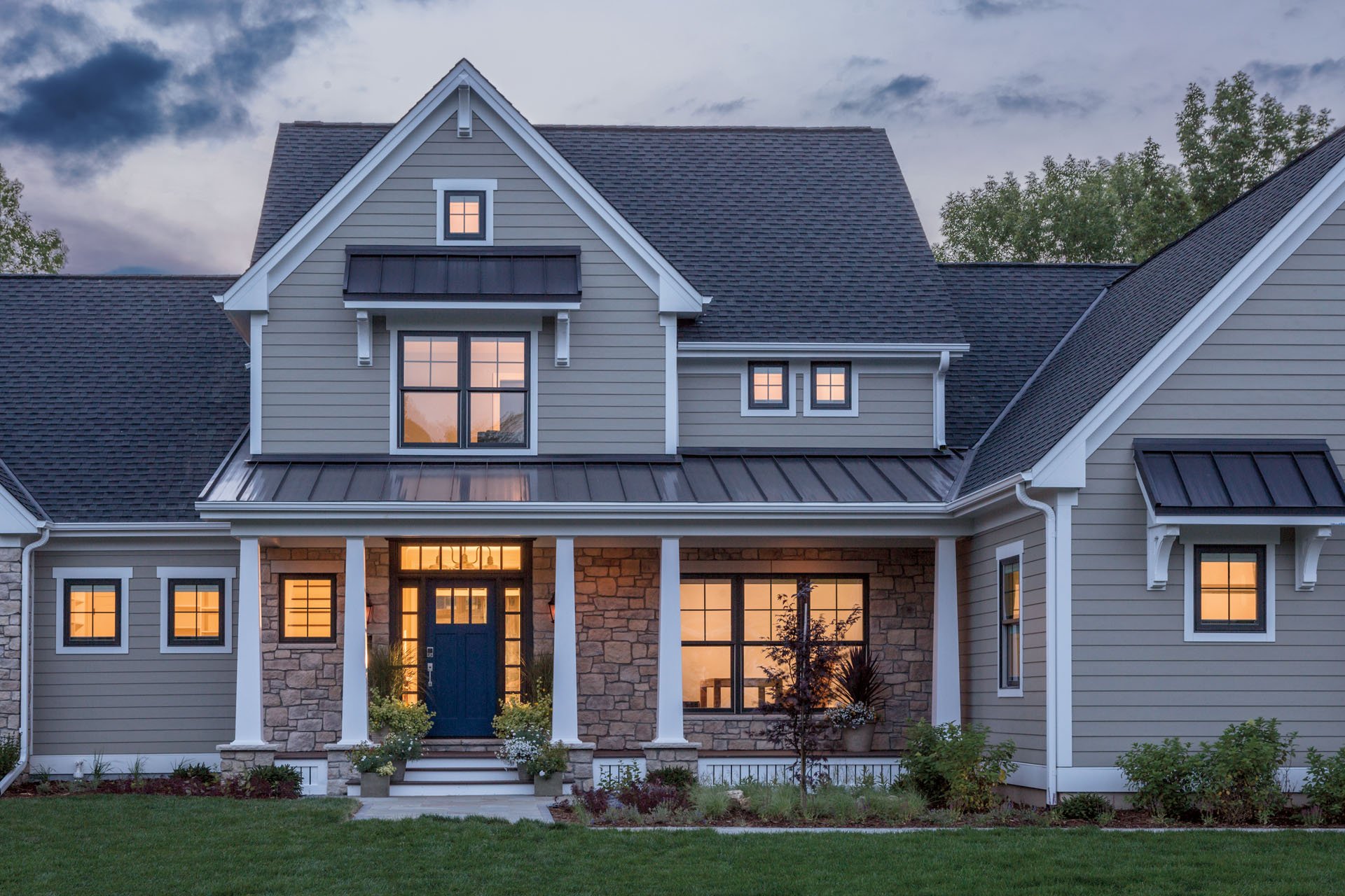 Large home with double-hung windows, gray siding, and brick exterior accent walls 